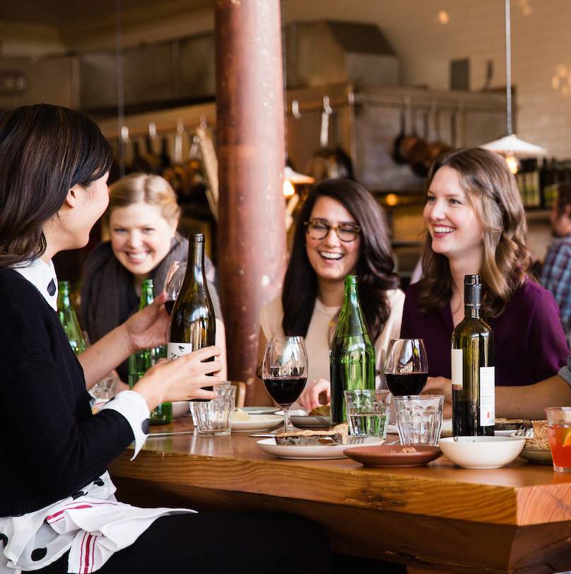 A group of four women at a restaurant laughing and talking
