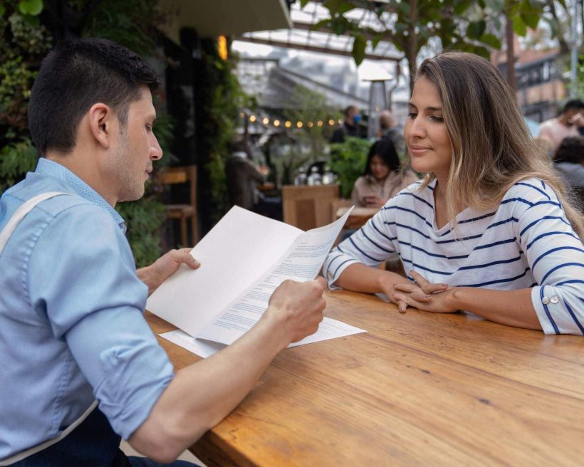 A restaurant managers interviews a candidate on the outdoor terrace of a restaurant